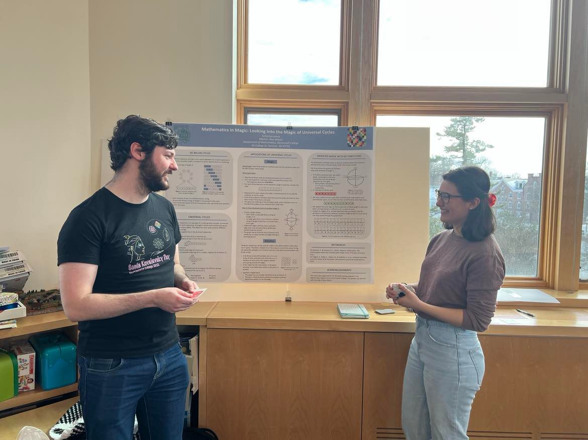 Two people standing in front of a poster